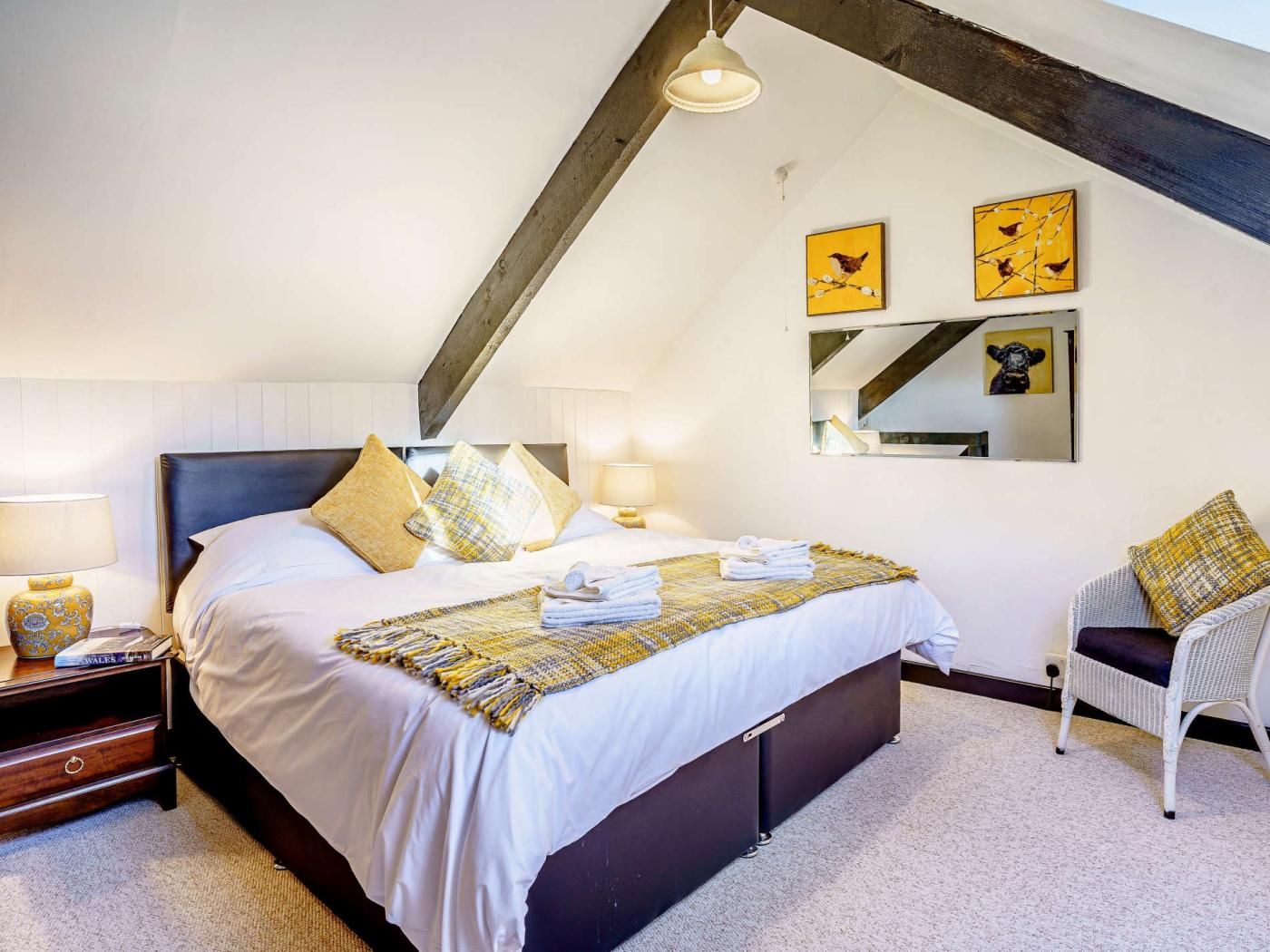 Une chambre à coucher avec un grand lit, une table de chevet, une chaise et des œuvres d’art accrochées au mur.
