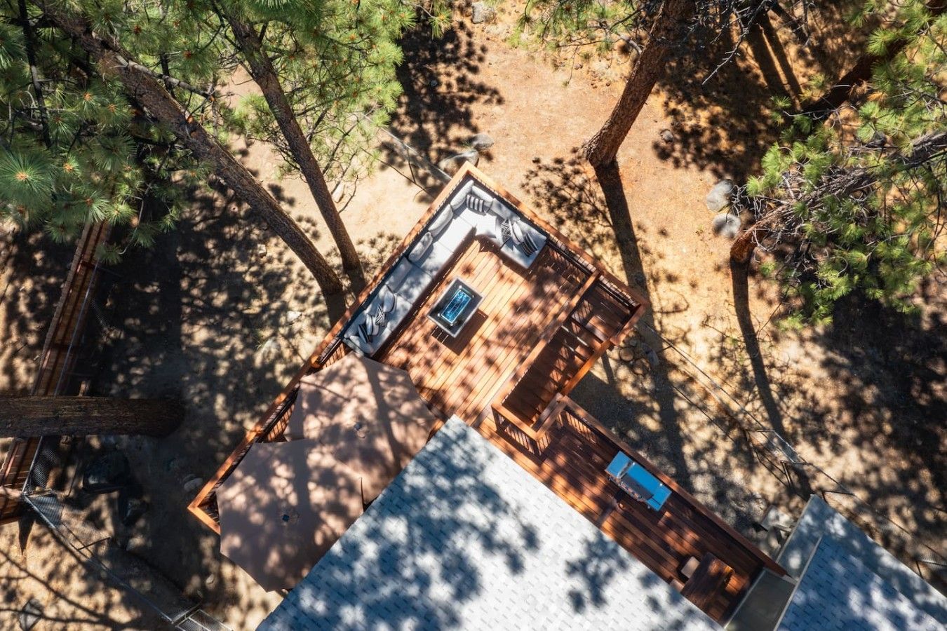 A wooden deck with a seating area and a small pool, surrounded by trees.