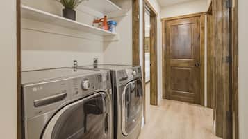 A laundry area with two front-loading washers and dryers, wooden flooring, and a wooden door.