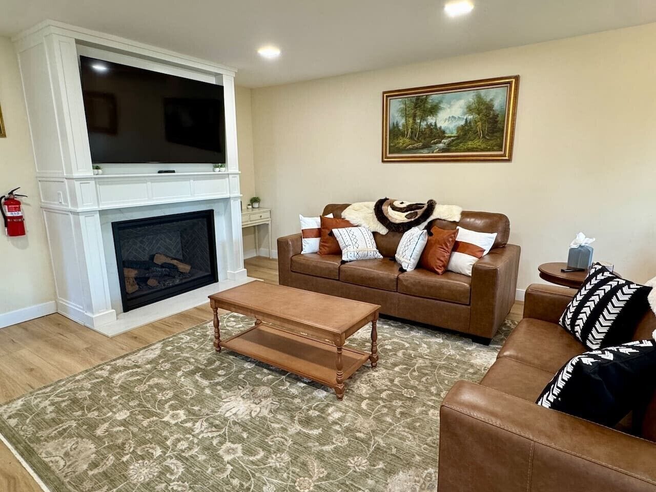 A living room with a fireplace, a brown sofa, a coffee table, and a patterned rug.