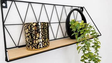 A shelf with a geometric metal frame, a patterned container, and a hanging plant.