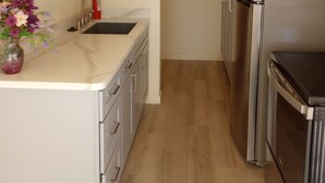 Eine schmale Küche mit Spüle, Schränken und einem Kühlschrank.