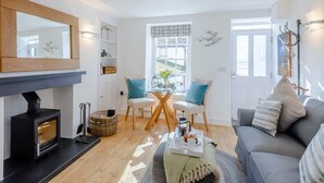 Un salon avec une cheminée, un coin repas avec une table et des chaises, un canapé et une grande fenêtre.