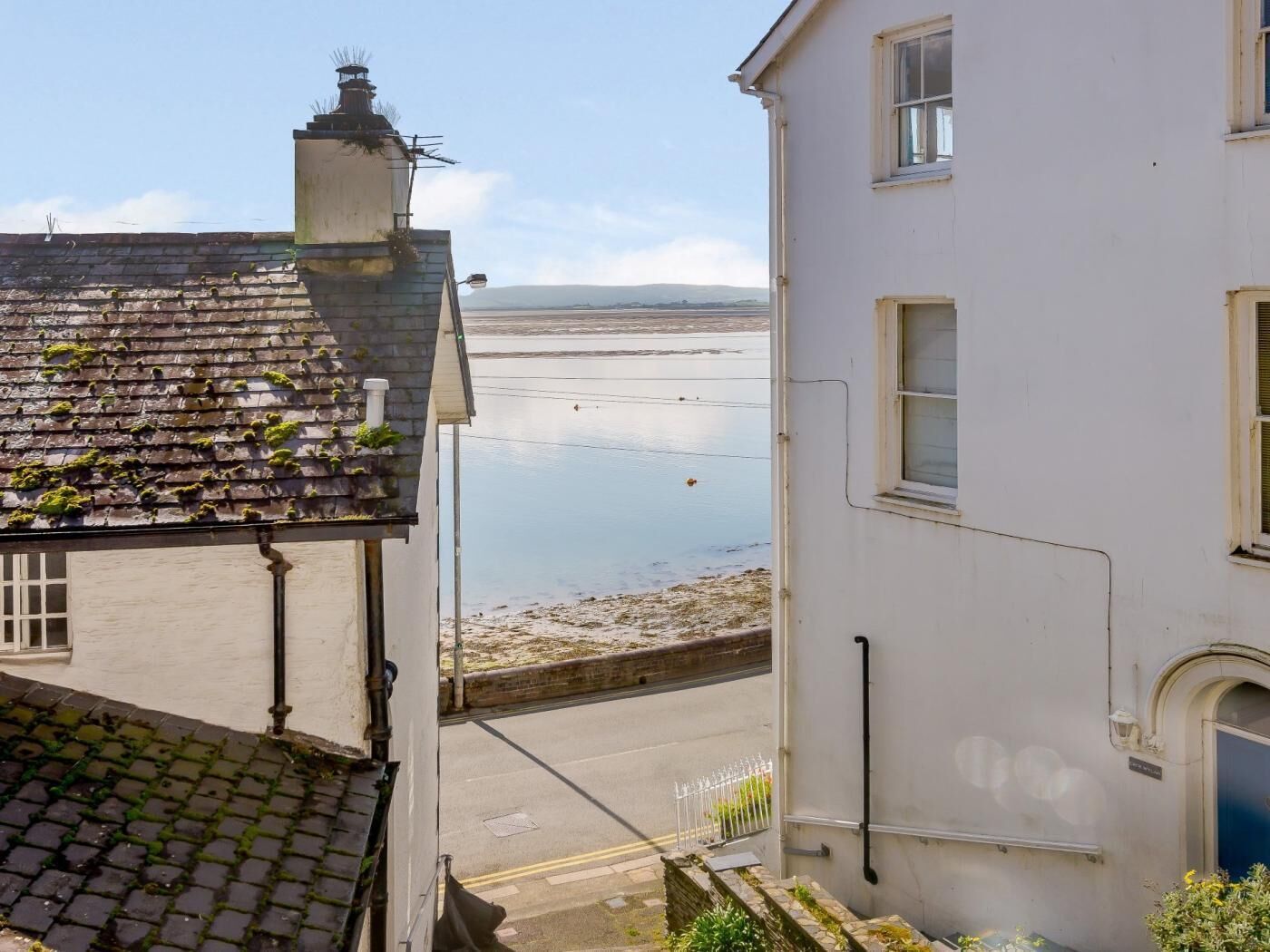 Um edifício costeiro com telhado ladrilhado, fachada branca e vista para o mar.