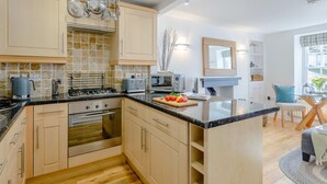 Une cuisine moderne dotée d’un îlot central, d’un four encastré, d’un micro-ondes et d’un porte-ustensiles suspendu.
