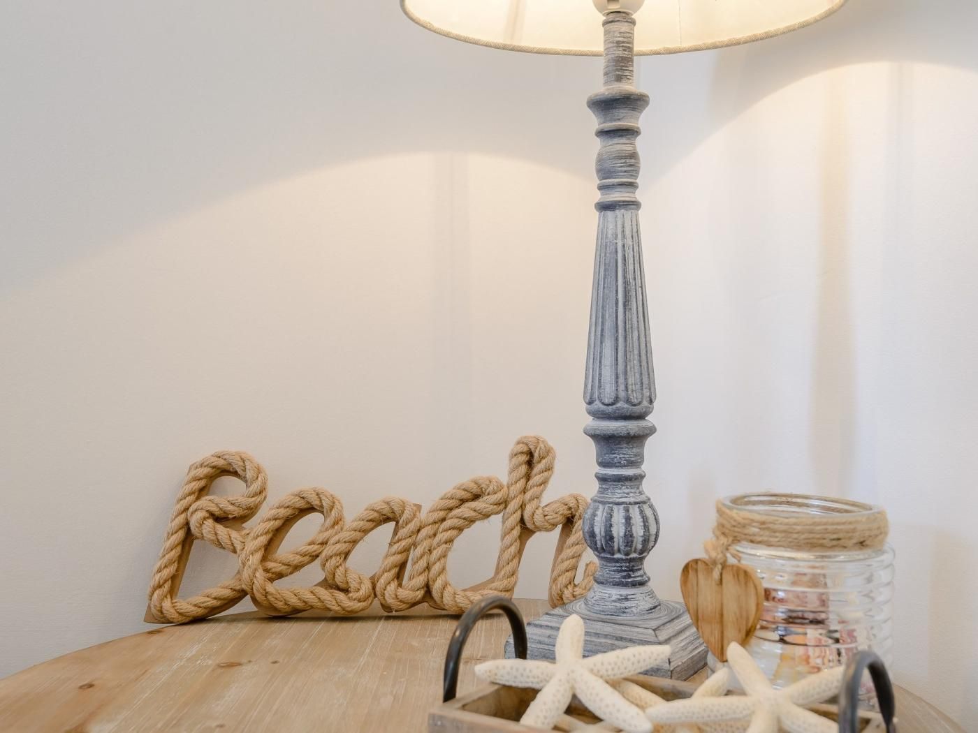 Eine Lampe mit strukturierter Basis, einer Seildekoration und einem Glas mit Seesternen.