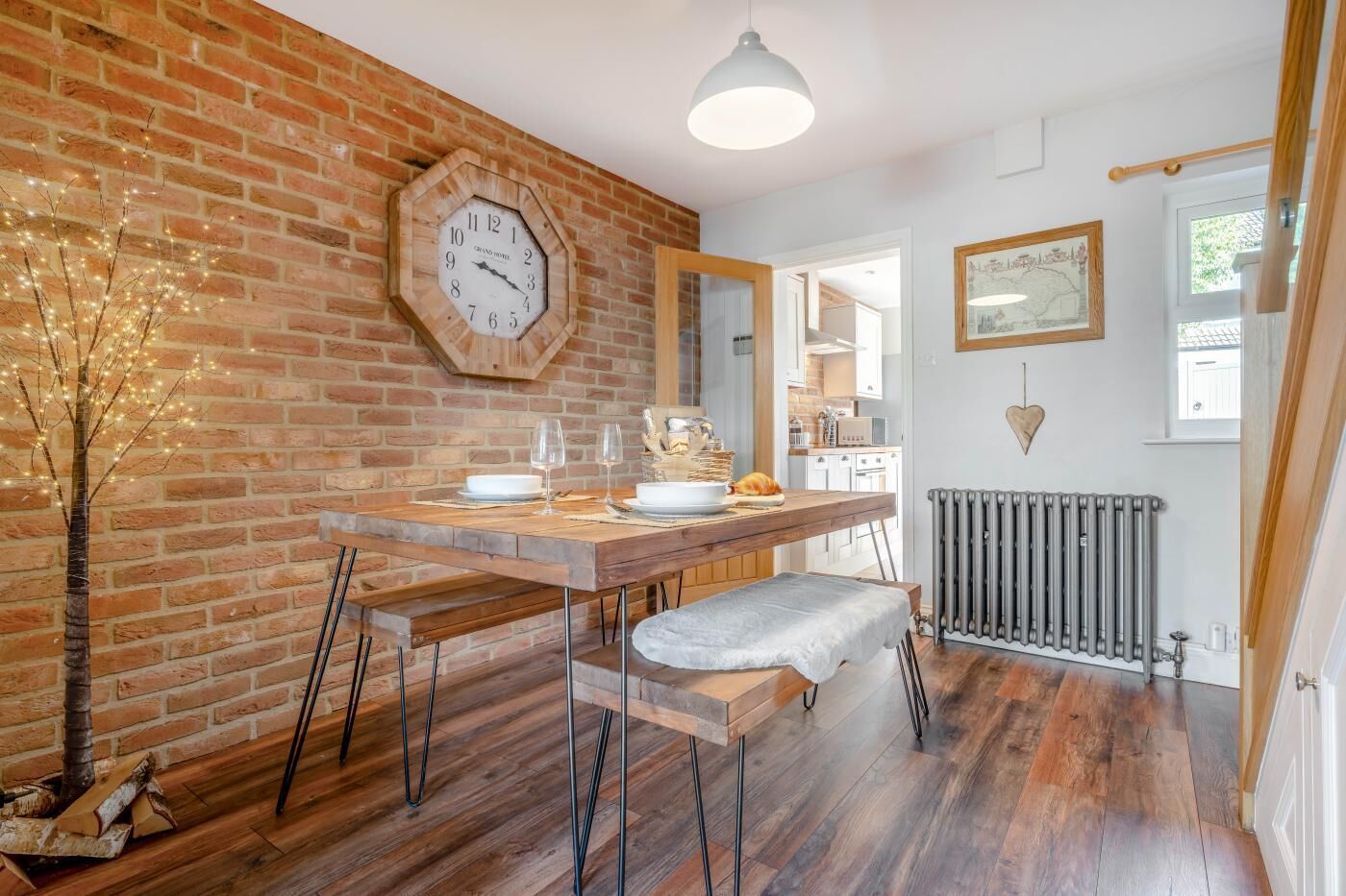 Un coin repas avec un mur en briques, une table en bois et une horloge.