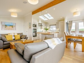 Ein modernes Interieur mit Sofa, Esstisch, Küchenzeile und Blick ins Freie.