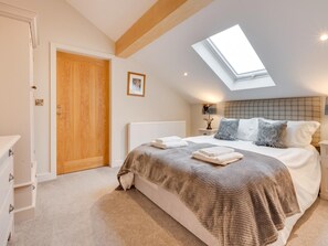 A bedroom with a skylight, a bed with a patterned blanket, a bedside table with a lamp, and a radiator. - 6 Bed in Scammonden (oc-79287) (Huddersfield)