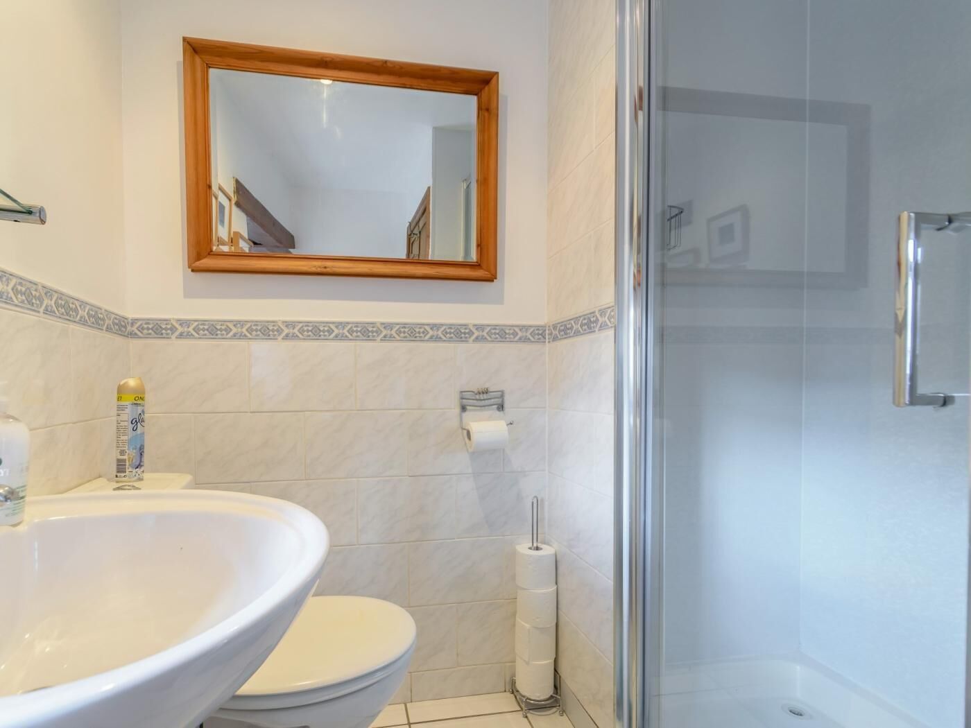 Une salle de bain avec un grand lavabo blanc, des toilettes, une douche et un miroir au-dessus du lavabo.