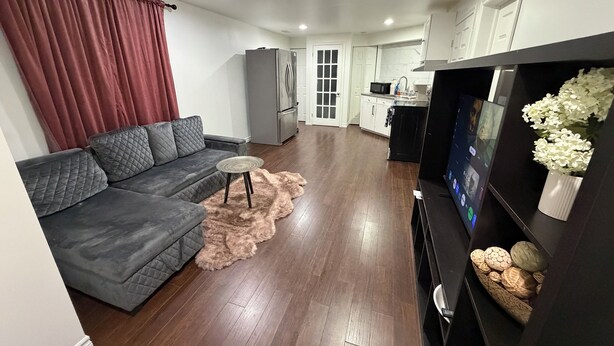 Ein modernes Wohnzimmer mit einem grauen Sofa, einem kleinen runden Tisch und einem Fernseher auf einem schwarzen Schrank.