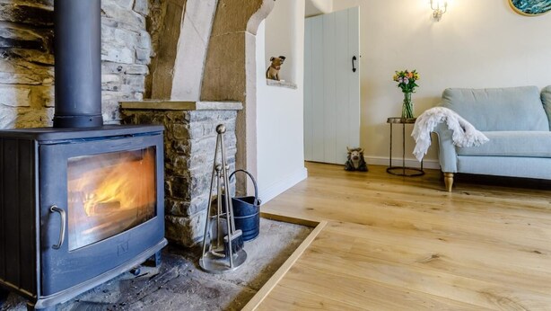 Ein gemütliches Zimmer mit Kamin aus Stein, einer Couch und Holzboden.