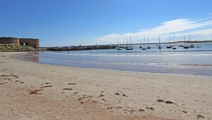 A beach with a sandy shore, a stone building, and several sailboats anchored in the water. - 3 Bed in Chathill (oc-79566) (Beadnell)