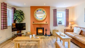 A living room with a fireplace, a television, a sofa, and a coffee table. - 3 Bed in Chathill (oc-79566) (Beadnell)