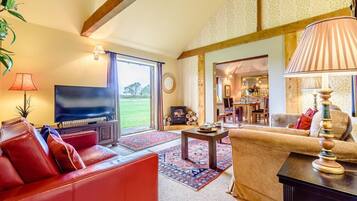 A spacious living room with a television, red leather sofa, and a fireplace.