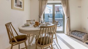 A dining area with a round table, wooden chairs, and a view through a glass door to the outside. - 2 Bed in Newton Tracey (oc-80381) (Newton Tracey)