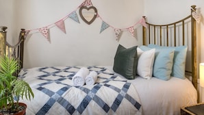 A bedroom with a bed, pillows, a quilt, a heart-shaped decoration, and a potted plant. - 2 Bed in Brecon (oc-bn016) (Talybont-on-Usk)