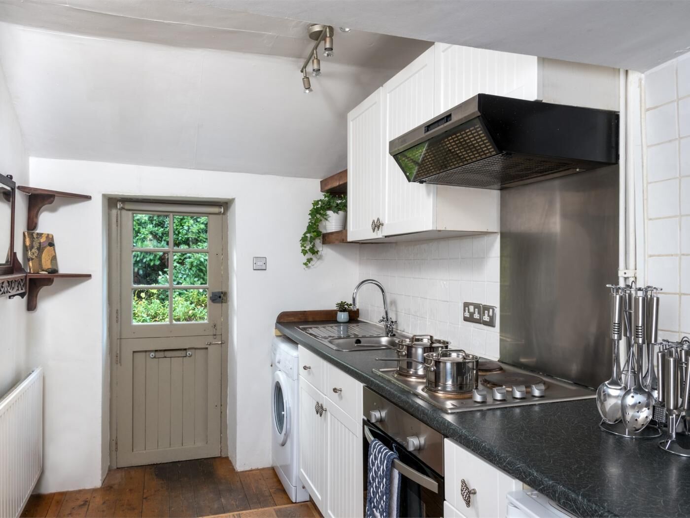 A compact kitchen with a washing machine, a sink, and a stove.