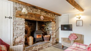 A cozy room with a stone fireplace, wicker baskets, a television, and striped furniture. - 2 Bed in Crickhowell (oc-bn023) (Llangynidr)