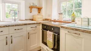 A kitchen with a sink, stove, oven, and window with a view of greenery. - 2 Bed in Crickhowell (oc-bn023) (Llangynidr)