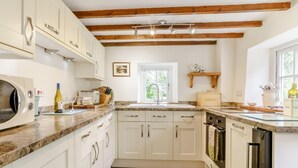 A kitchen with white cabinets, a granite countertop, a wooden ceiling, and a patterned rug. - 2 Bed in Crickhowell (oc-bn023) (Llangynidr)