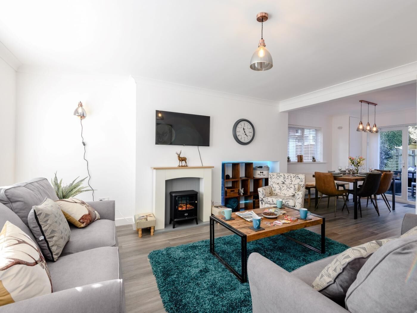 A modern living room with a fireplace, a television, and a dining area with chairs and a table.