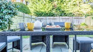 A patio table with chairs, a teapot, and a plate of food. - 4 Bed in Brockenhurst (oc-80420) (Brockenhurst)