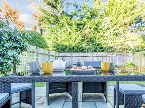 A patio table with chairs, a teapot, and a plate of food. - 4 Bed in Brockenhurst (oc-80420) (Brockenhurst)