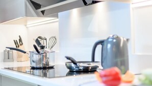 A modern kitchen with a stove, kettle, and utensils. - 4 Bed in Brockenhurst (oc-80420) (Brockenhurst)