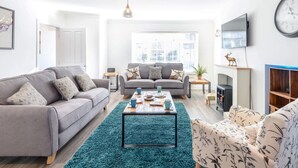 A modern living room with a grey sofa, a blue rug, and a coffee table. - 4 Bed in Brockenhurst (oc-80420) (Brockenhurst)