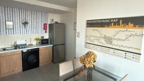 Een moderne keuken met een vaatwasser, koelkast, en een eethoek met een glazen tafel en stoelen.