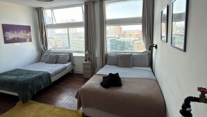 Een hotelkamer met twee bedden, uitzicht op de stad en een stadslandschap op de muur.