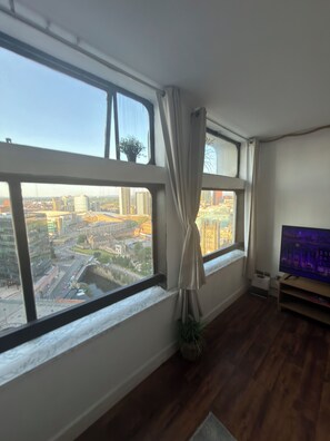 A room with a large window, a flat-screen TV, and a plant. - Manchester City Centre/ Prime Location Apartment (Salford)