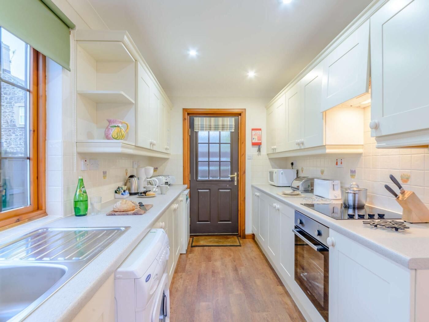 A compact kitchen with white cabinets, a built-in oven, a microwave, and a sink.