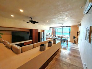 Un área de estar moderna con sofá, televisor y comedor.