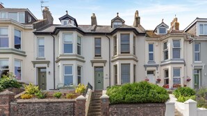 A row of terraced houses with bay windows, a stone wall, and a small garden. - 2 Bed in Brixham (oc-80453) (Brixham)