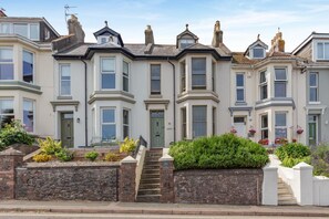A row of terraced houses with bay windows, a stone wall, and a small garden. - 2 Bed in Brixham (oc-80453) (Brixham)