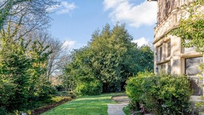 A well-maintained garden with a stone pathway leading to a building with classical architecture. - 2 Bed in Bideford (oc-80350) (Northam)