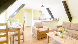 A cozy loft-style room with a dining area, a sofa, and a kitchen. - 2 Bed in Bideford (oc-80350) (Northam)