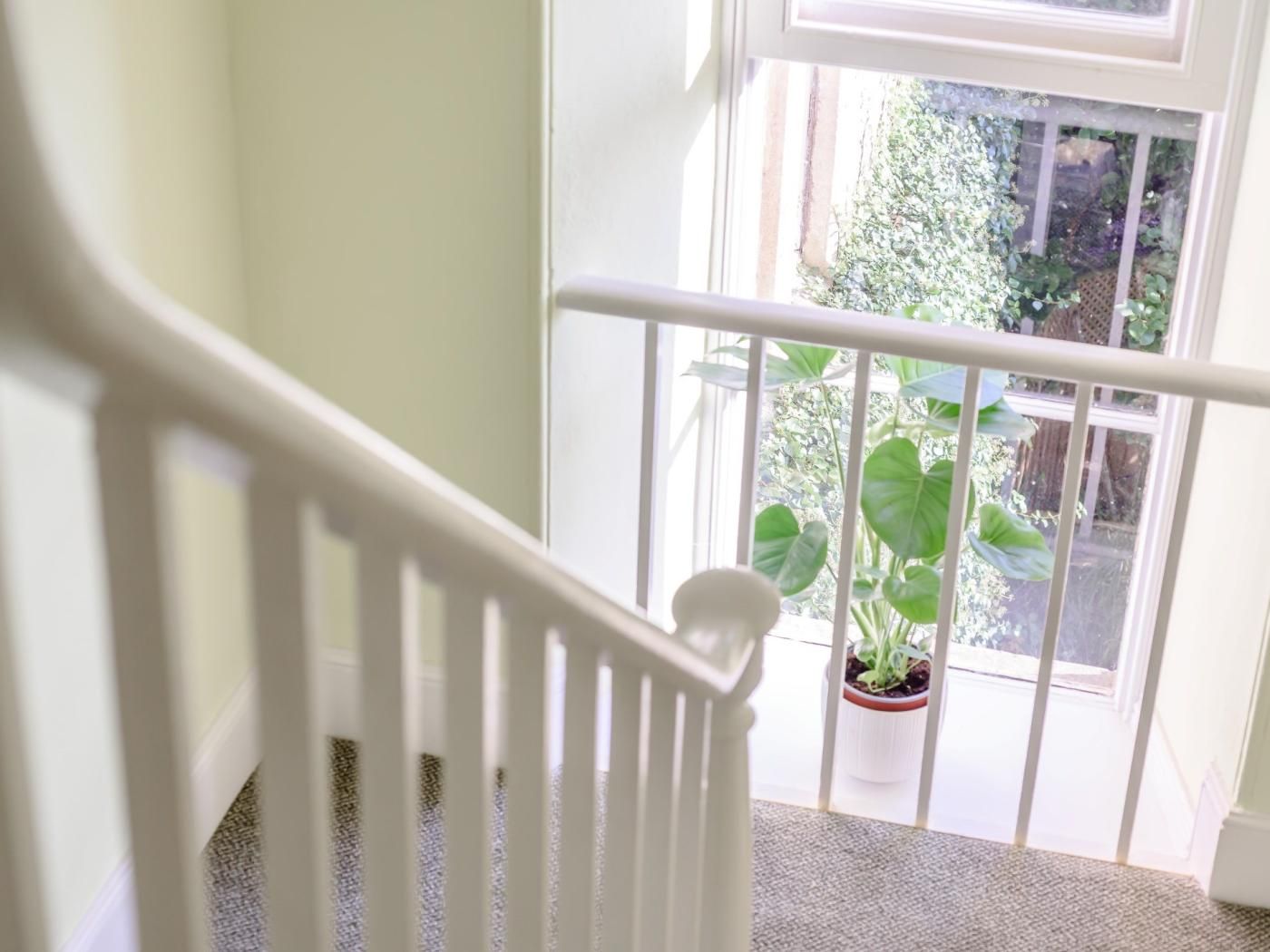 A staircase with a white railing leading to a balcony with a potted plant.