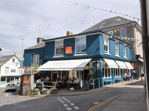 Un edificio blu con una tenda bianca con scritto "The Cosy Cafe".