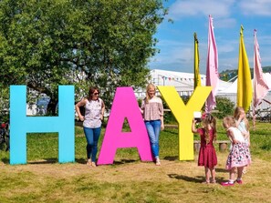 A grassy outdoor area with large colorful letters spelling 'HAY' and a white tent structure in the background. - 2 Bed in Hereford (oc-bn433) (Hay-on-Wye)