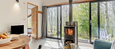 Una sala de estar moderna con un ventanal grande, una chimenea, una mesa de comedor con sillas y un sofá.