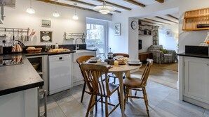 A modern kitchen with wooden beams, a dining table with chairs, and a view of the city. - 2 Bed in Ashbourne (oc-80458) (Parwich)