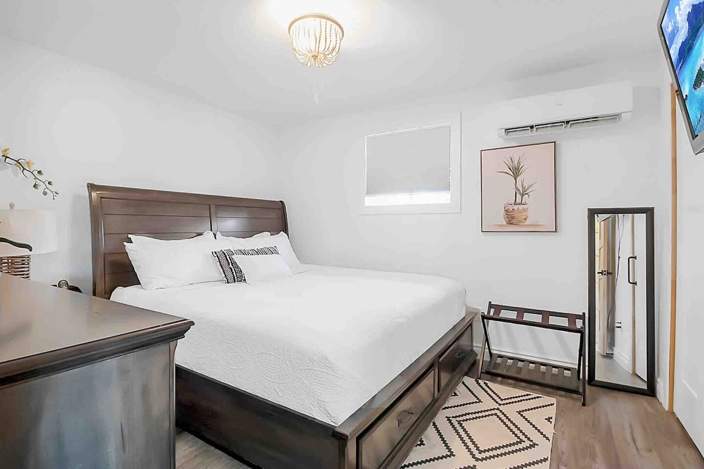 Una camera da letto con un letto, un comodino, una lampada, un condizionatore d'aria, un quadro incorniciato e una porta.