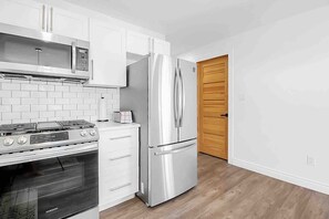 A modern kitchen with white cabinetry, a stainless steel refrigerator, a built-in oven, and a microwave. - 2 bedroom Getaway/Lake St. Claire, Canada/kayak (Belle River)
