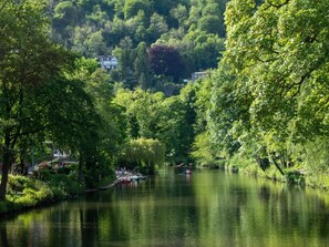 A river with boats, surrounded by dense greenery and houses in the background. - 2 Bed in Matlock (oc-80535) (Matlock)