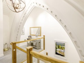 A high-ceilinged room with a wooden staircase, a chandelier, a mirror, and a framed poster. - 2 Bed in Matlock (oc-80535) (Matlock)