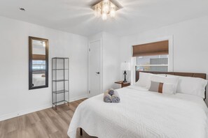 Una camera da letto con un letto grande, un comodino con una lampada, uno specchio, un armadio e una finestra con persiane.
