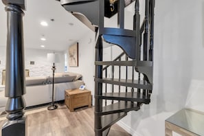 Ein modernes Interieur mit einer Wendeltreppe, einem Sofa, einer Lampe und einem kleinen Holztisch.